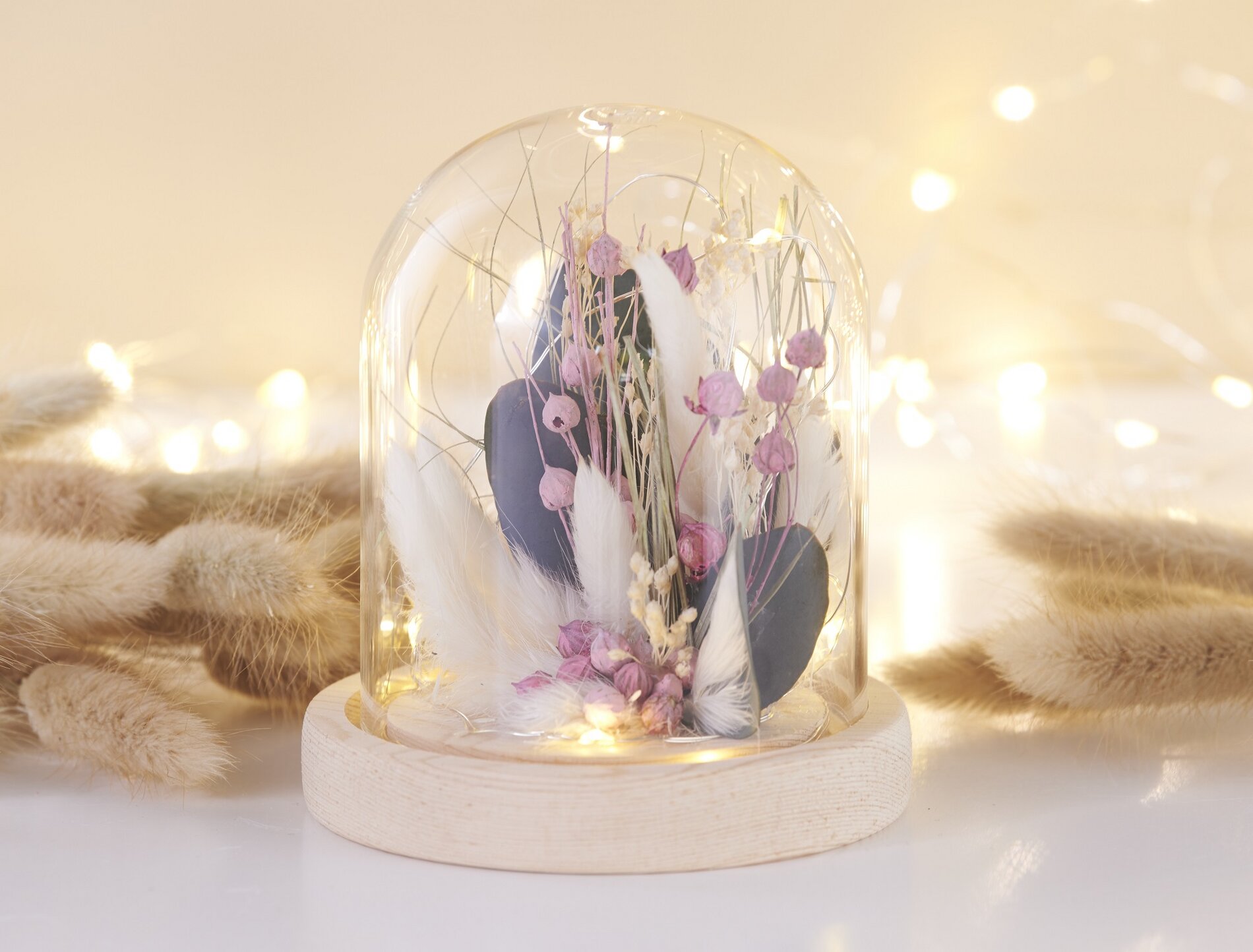 Beleuchtete Glasglocke mit Trockenblumen